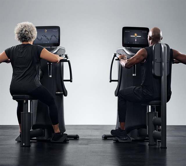 Zwei Personen trainieren an EGYM-Kraftgeräten mit Bildschirm